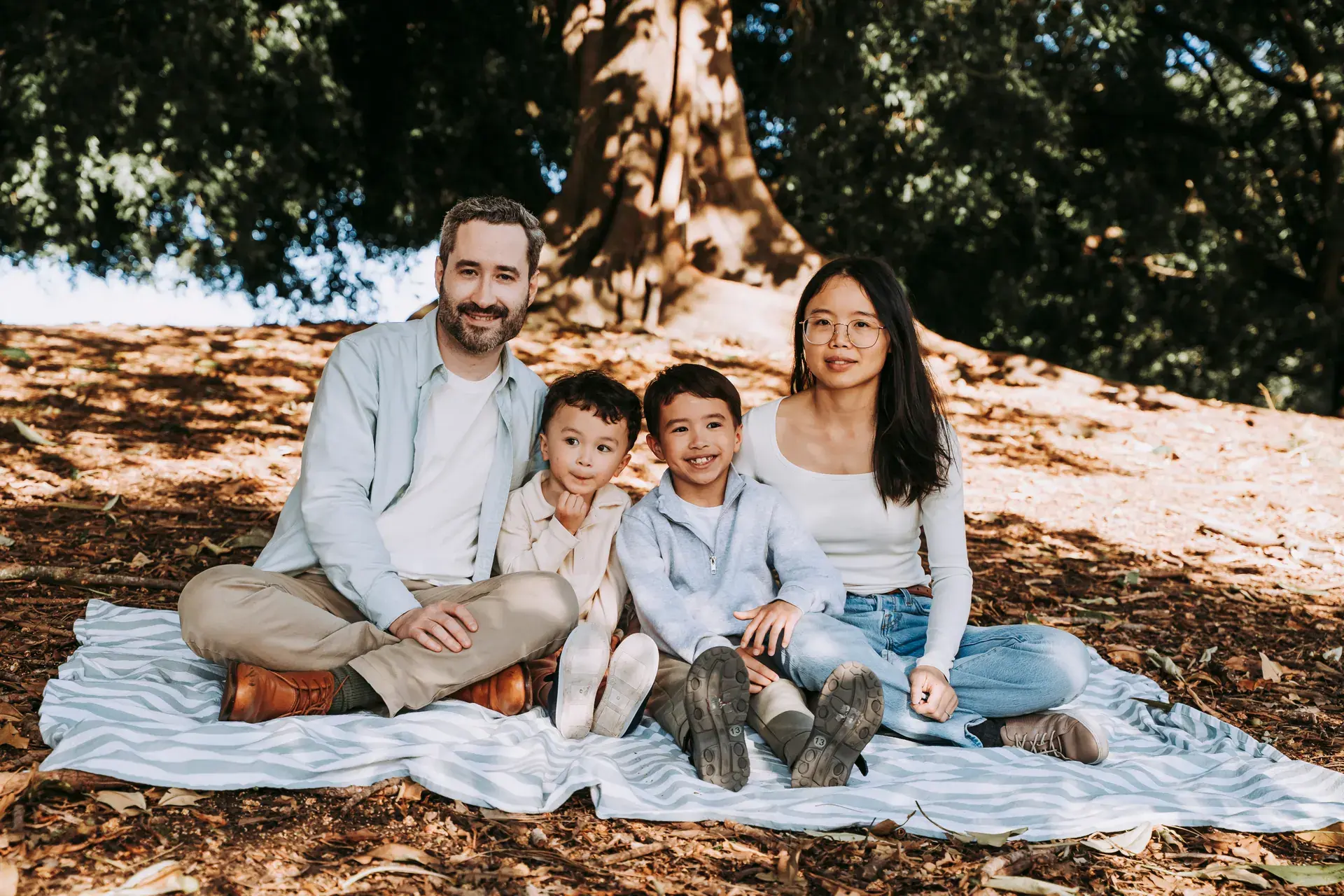 Family photographed together on a rug under a tree